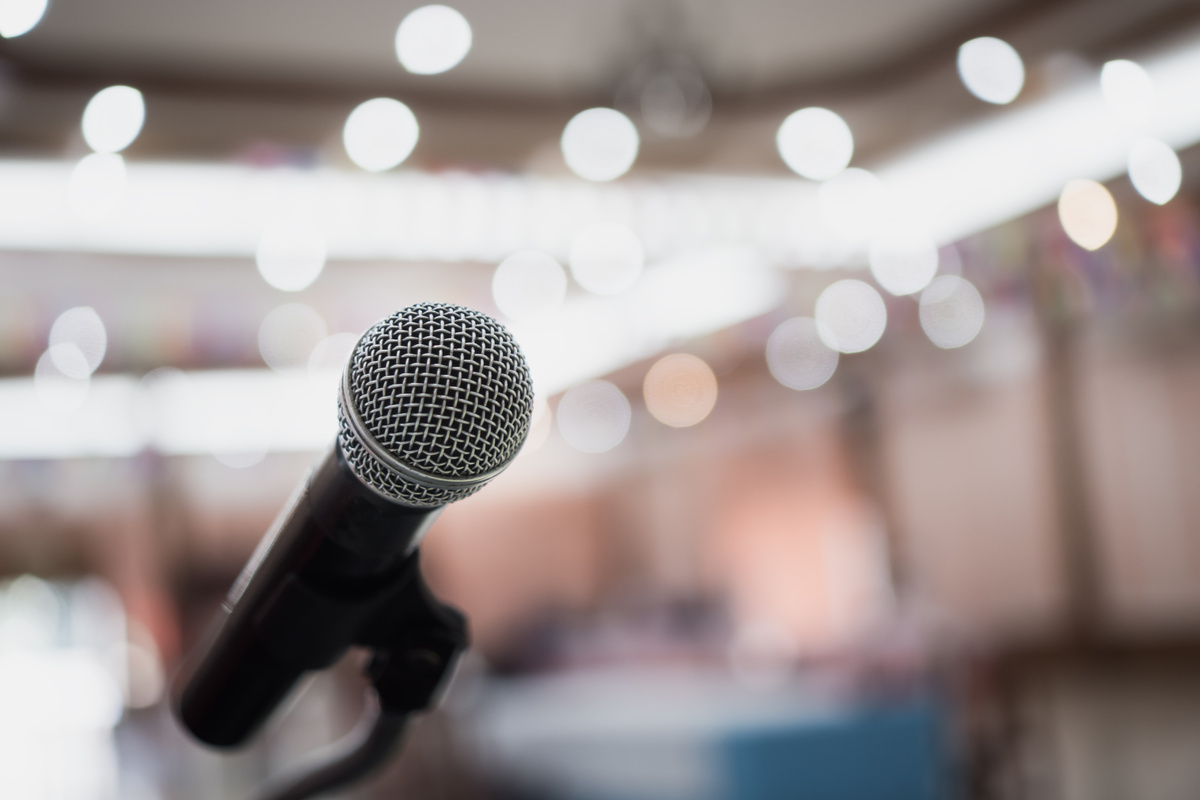 Front Microphone on abstract conference hall prepare for speaker on stage in seminar room, Business meeting and education in teaching classroom or Event light convention hall Background.